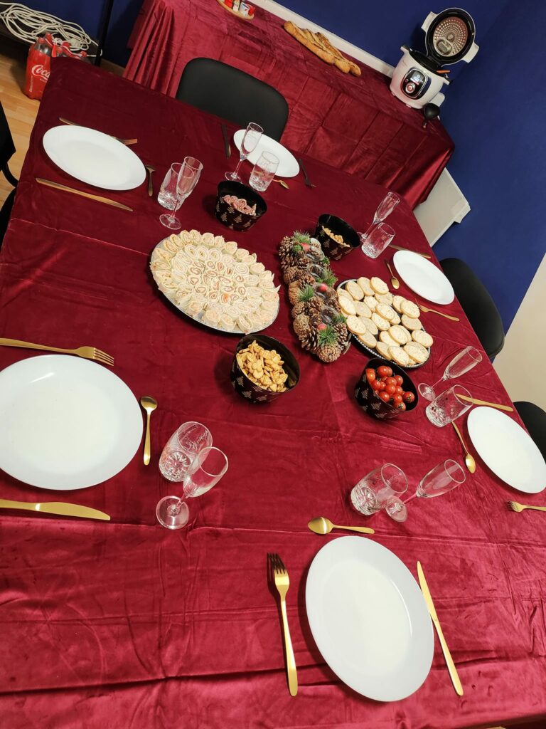 une table dresser d'une nappe rouge avec des couvert blanc et des assiettes planches avec un apéritif poser dessus de notre Centre de bien-être avec salle pour tout casser près de Dieppe